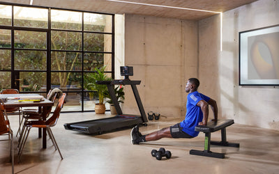 Fitnessgeräte für zuhause - Ein Mann trainiert an einer Ahntelbank. Ein Laufband ist im Hintergrund zu sehen.